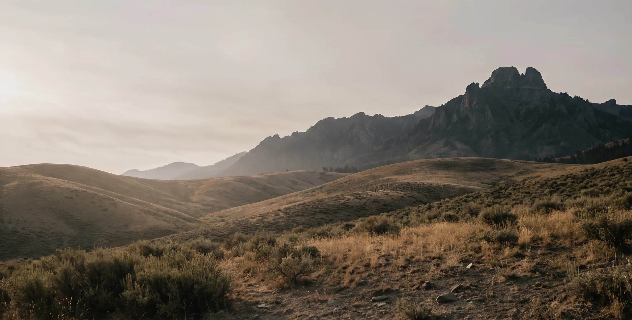 Golden foothills beneath a Western mountain ridge, an imagined landscape